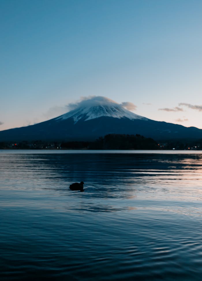 Capture the tranquility of Mount Fuji reflected in a calm lake at twilight.