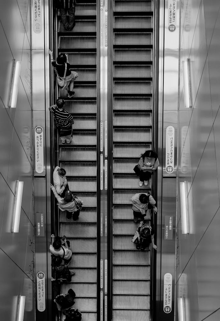 Black and white view of people on an escalator in Setagaya City, Tokyo, highlighting daily urban life.
