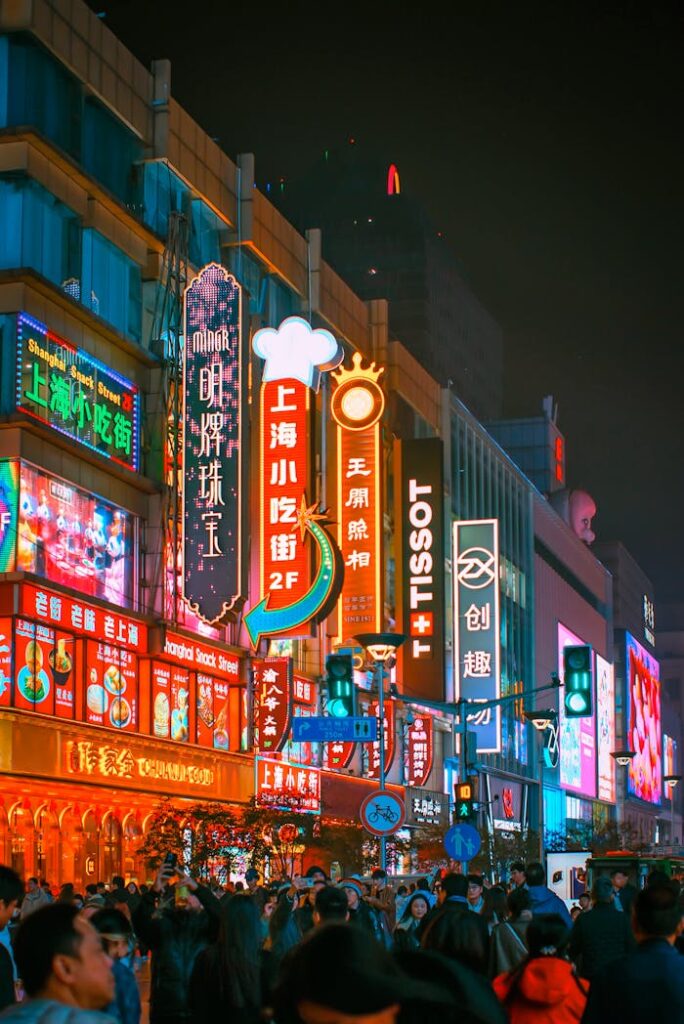 Vibrant night scene of Shanghai's Nanjing Road with colorful neon signs and a bustling crowd.