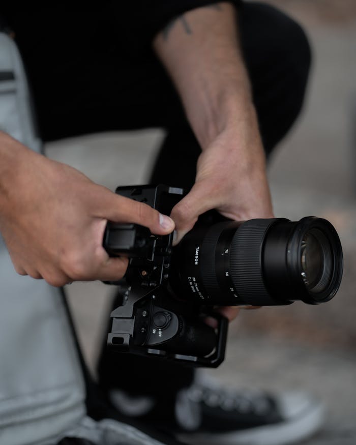 Close-up view of a person adjusting a DSLR camera outdoors, showcasing photography equipment.
